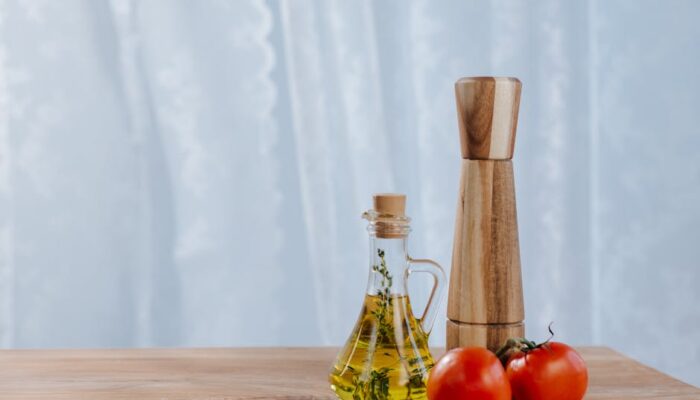 Fresh ingredients including olive oil, tomatoes, and a pepper mill on a kitchen table. - Photo by Ron Lach on Pexels