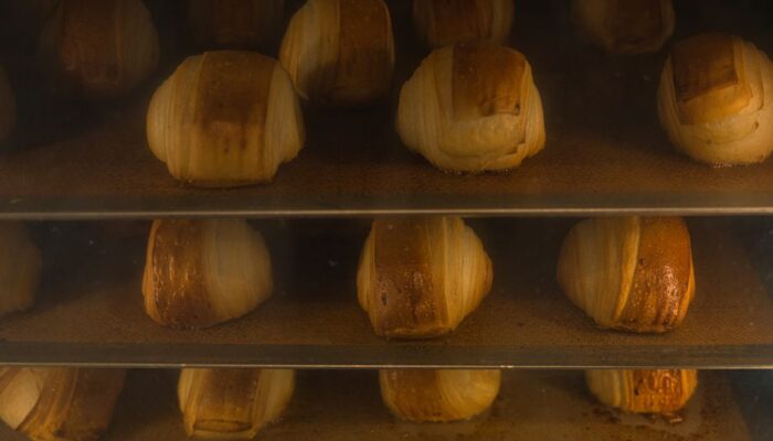Golden croissants baking in an artisan oven, showcasing delicious pastry textures. - Photo by Travel with Lenses on Pexels