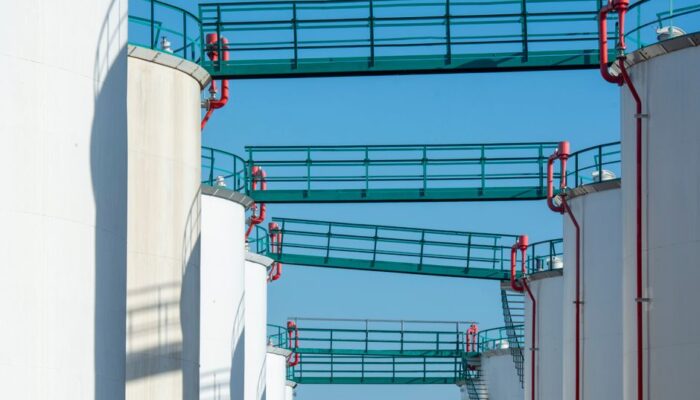 Modern industrial storage tanks with walkways against a clear blue sky. - Photo by Jan van der Wolf on Pexels