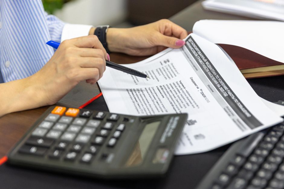 Close-up of a person analyzing financial documents using a calculator and pen. - Photo by Bia Limova on Pexels