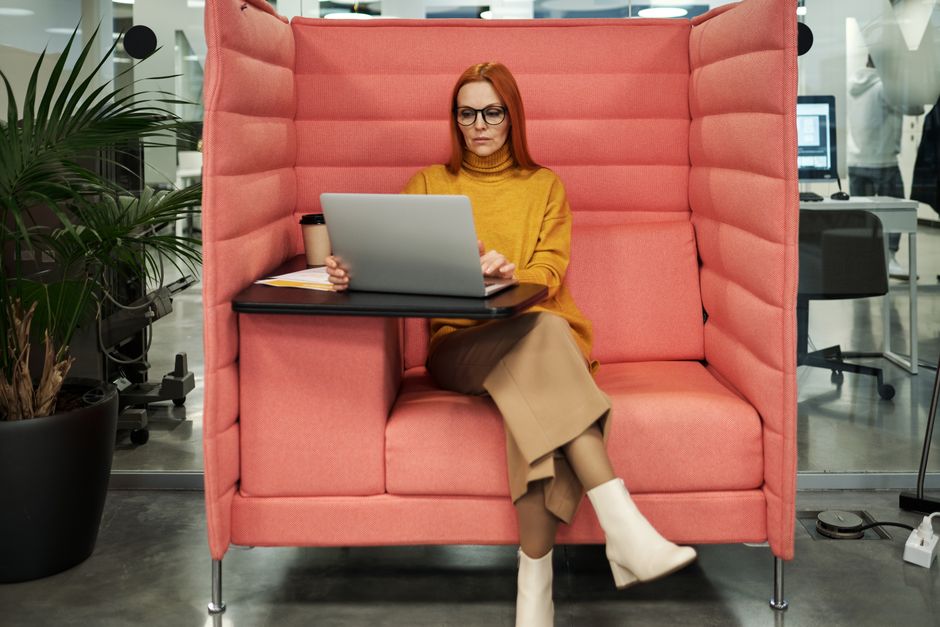 Businesswoman in a yellow sweater working on a laptop in a modern office booth setting, exhibiting style and focus. - Photo by Jack Sparrow on Pexels