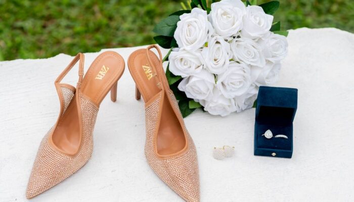 Elegant display of wedding shoes, white roses, and jewelry on a table. - Photo by Kofi Bush caleb on Pexels