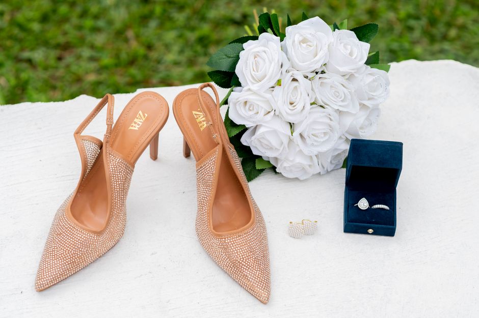 Elegant display of wedding shoes, white roses, and jewelry on a table. - Photo by Kofi Bush caleb on Pexels