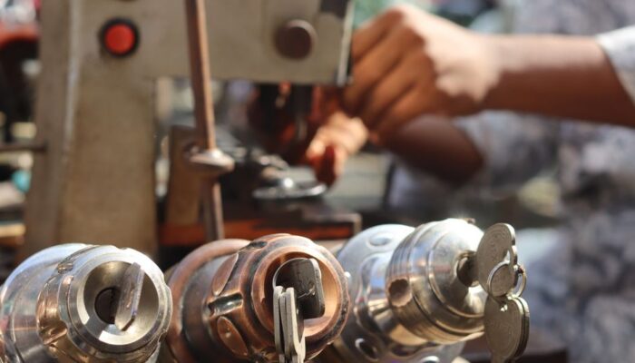 Close-up image of locksmith tools and hands working with a key machine outdoors. - Photo by Saad Bin Hasan on Pexels